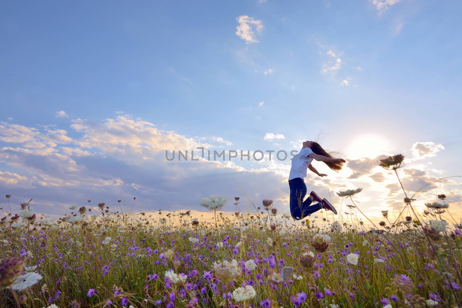 Beautiful teenage girl jumping on summer field
