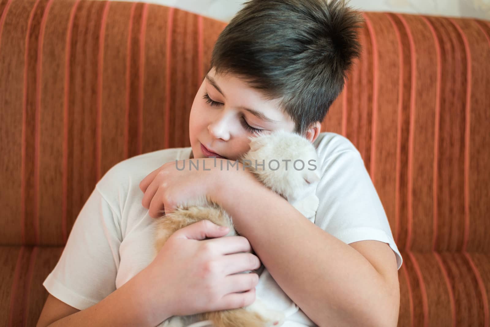 Boy teenager holding kitten in her arms by olgavolodina