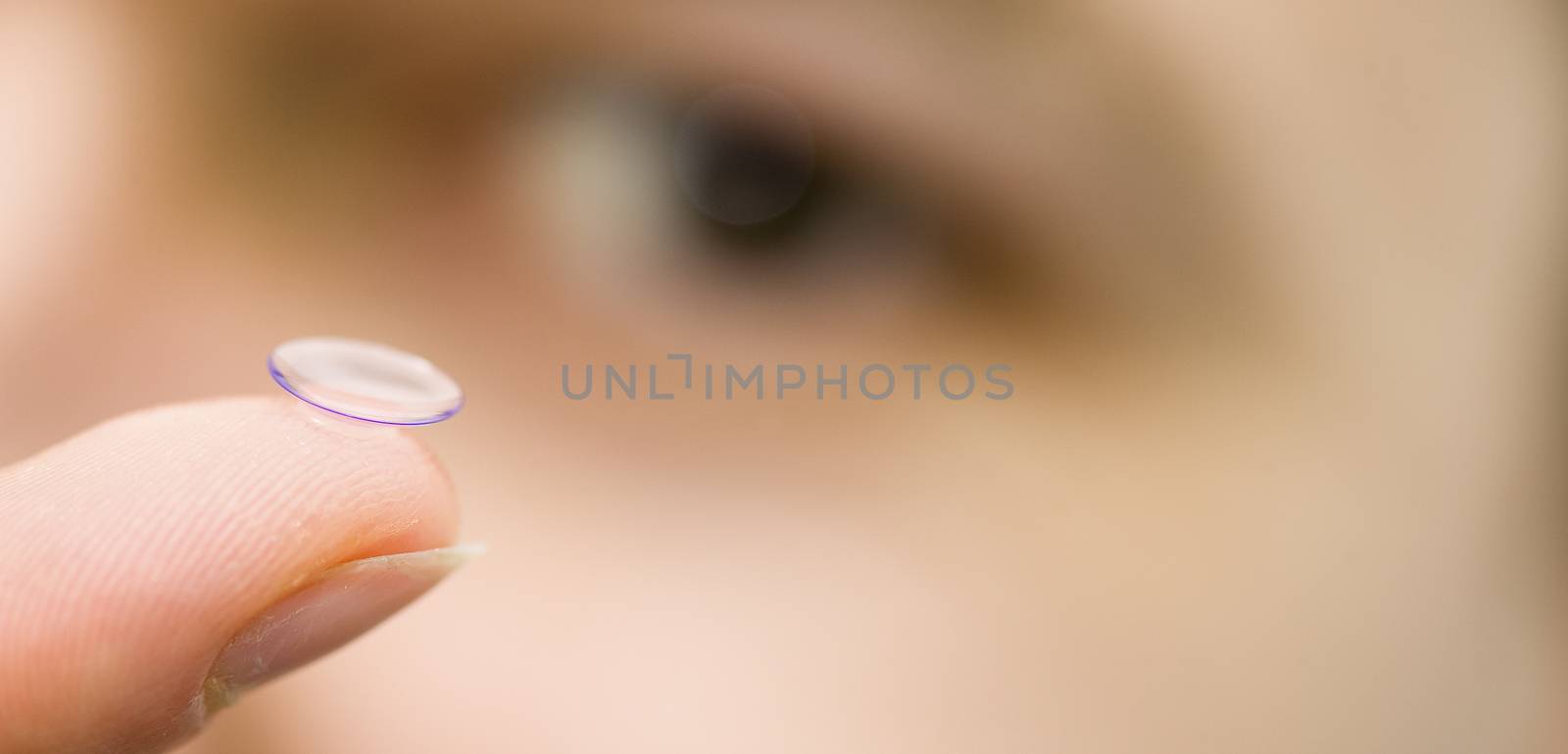 Contact lens on finger on eye background, France