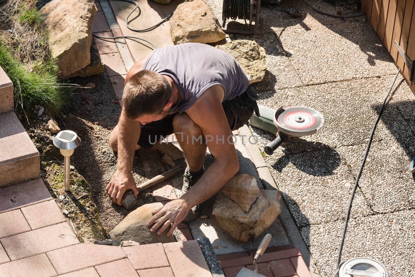 Man Build a dry wall in the garden. In the background, various tools.