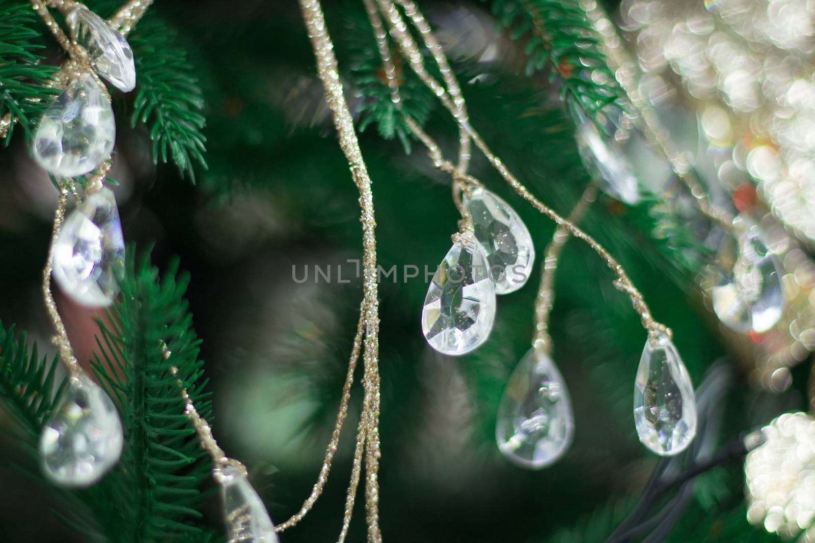 Christmas and New Year seasonal background of green tree with bright diamond drops and golden ornaments