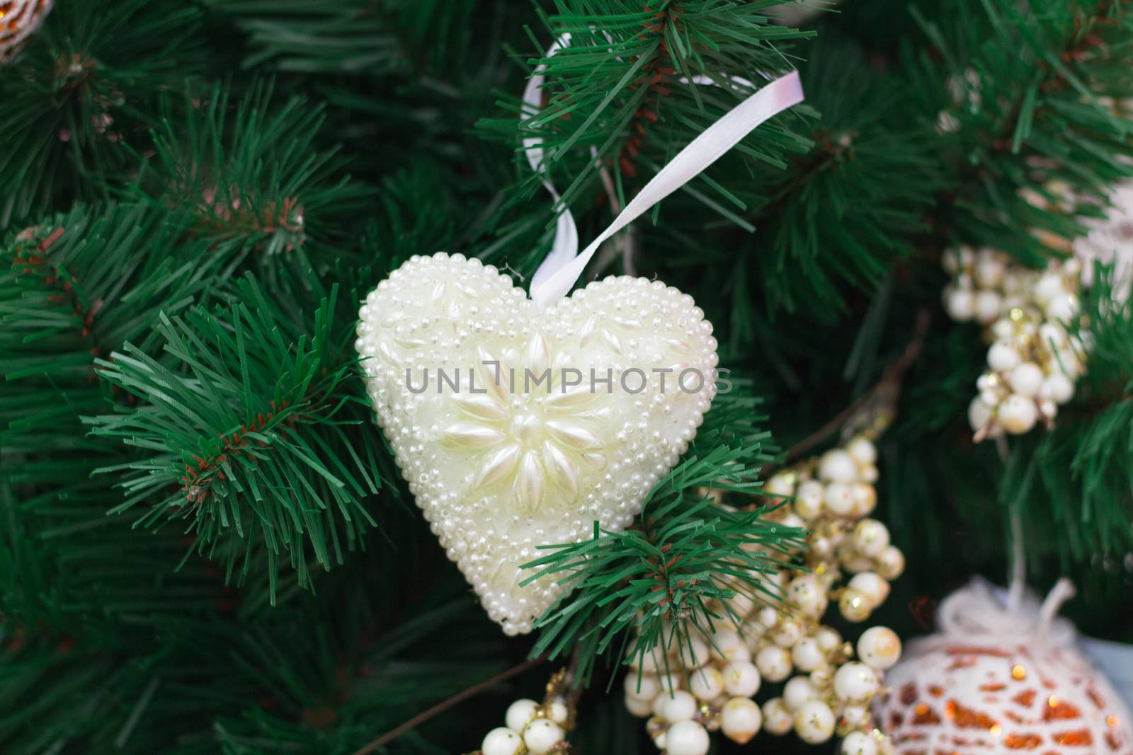 Christmas and New Year seasonal decoration, green tree branches with white heart and golden ornaments