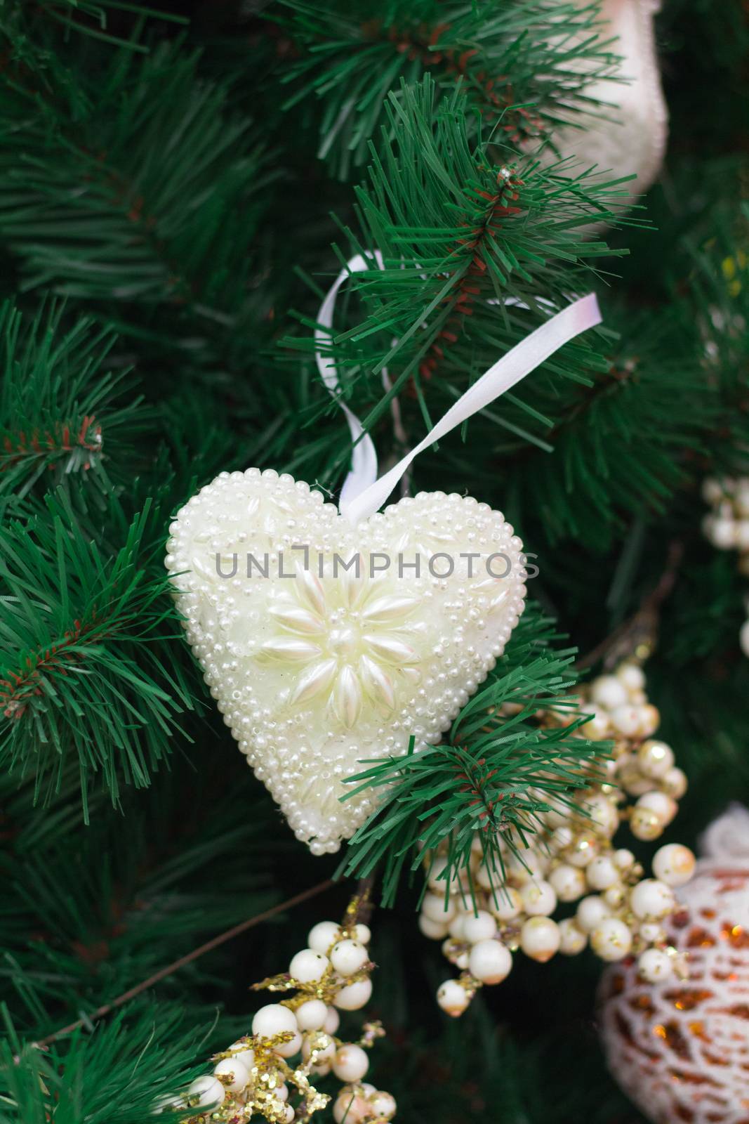 Christmas and New Year seasonal decoration, green tree branches with white heart and golden ornaments
