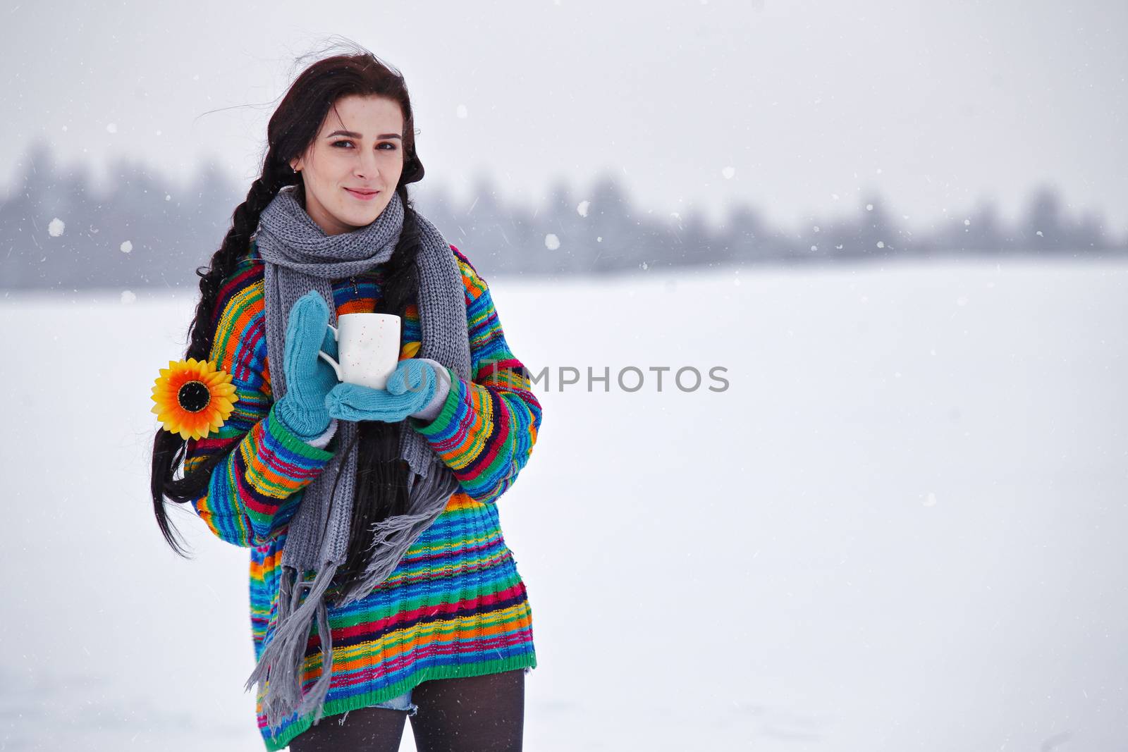 Beautiful young woman in a sweater on a winter walk with a cup of coffee. Looking At Camera