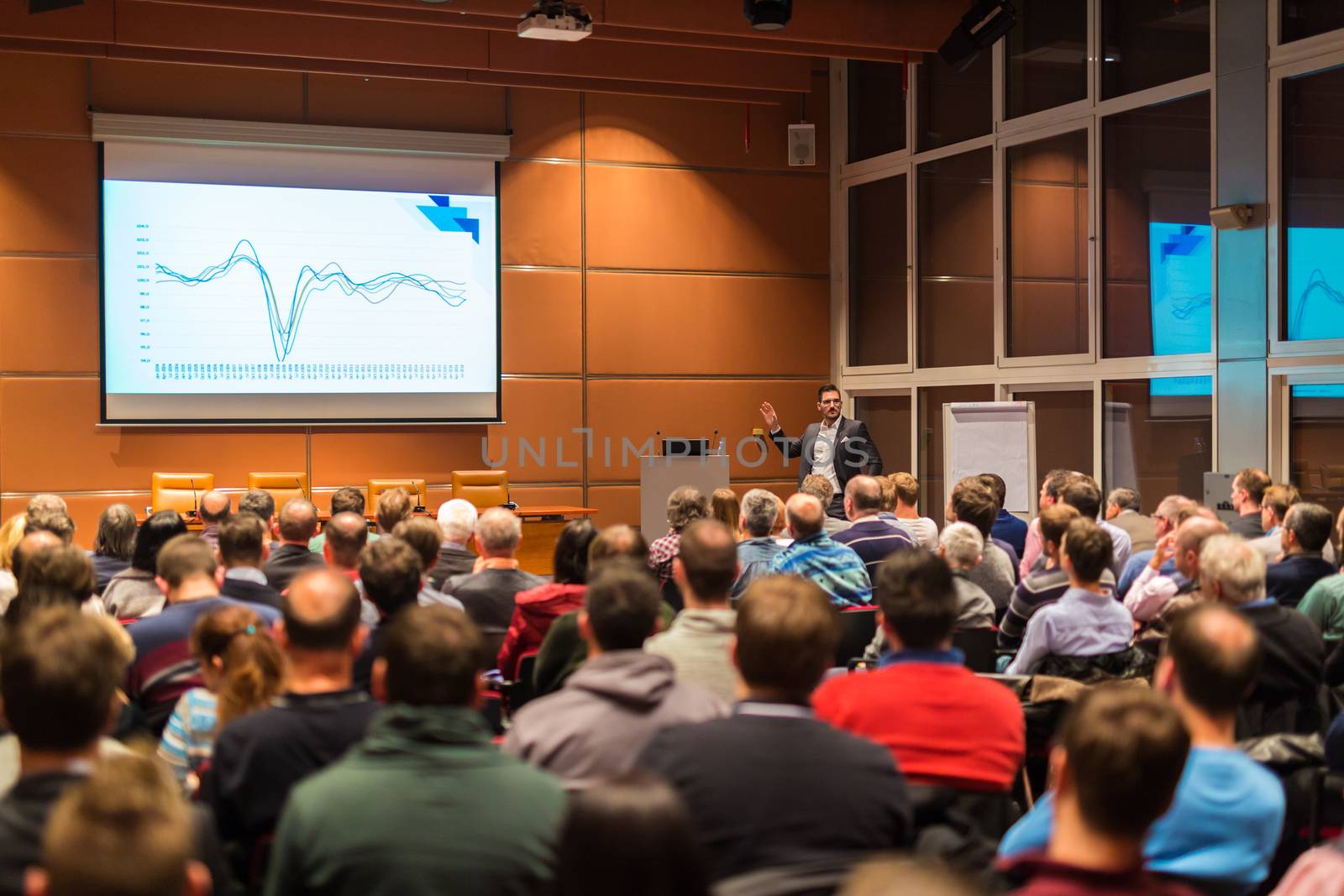 Speaker giving a talk in conference hall at business event. Audience at the conference hall. Business and Entrepreneurship concept.