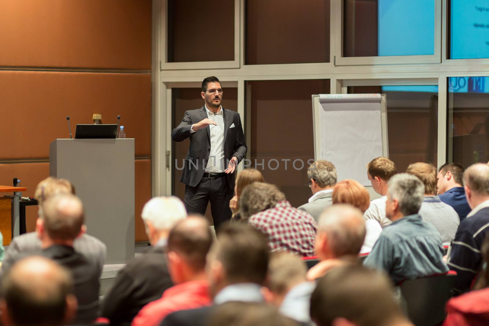 Speaker giving a talk in conference hall at business event. Audience at the conference hall. Business and Entrepreneurship concept.