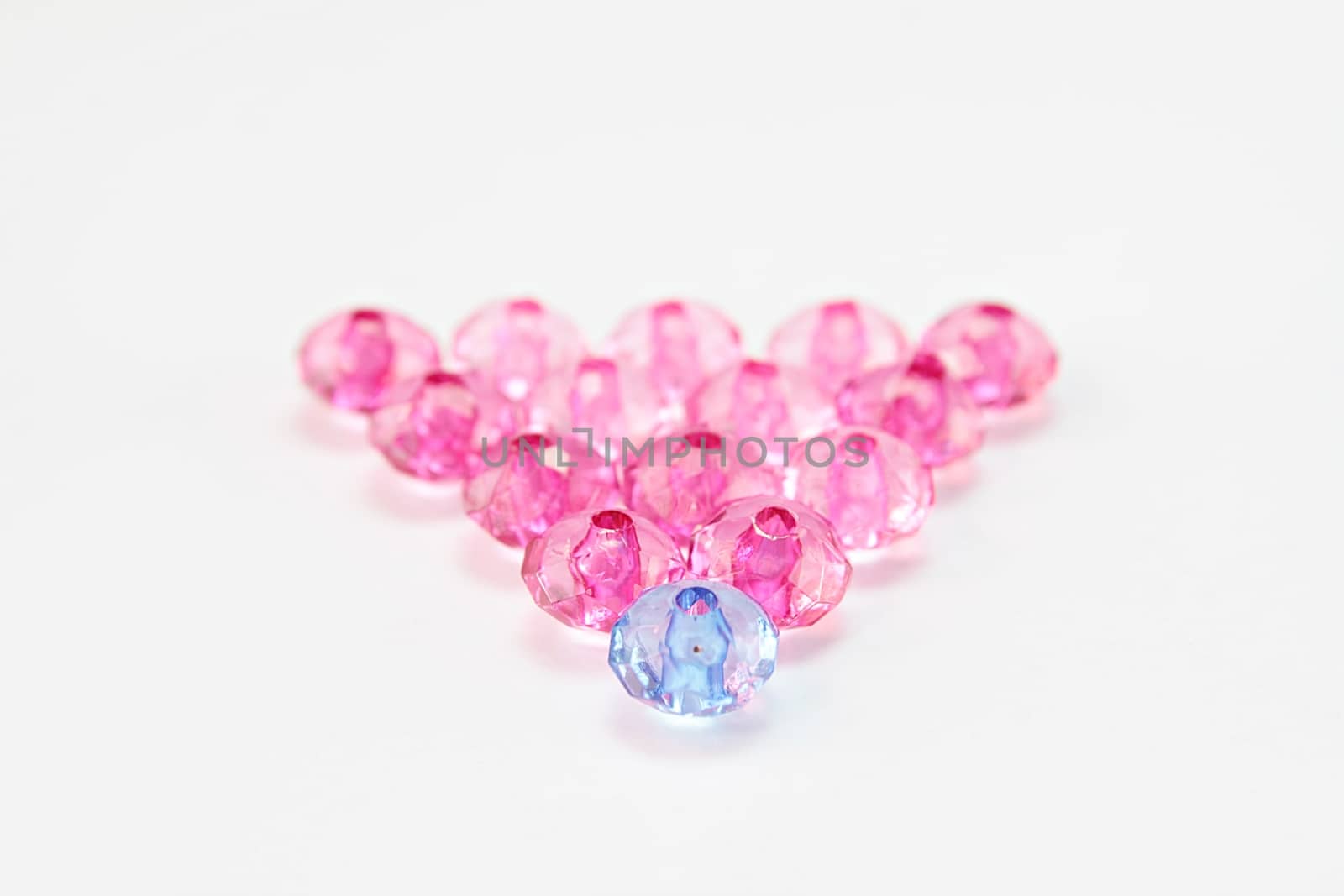 Leadership or teamwork concept : Blue crystal bead leading pink ones, blue crystal bead among pink