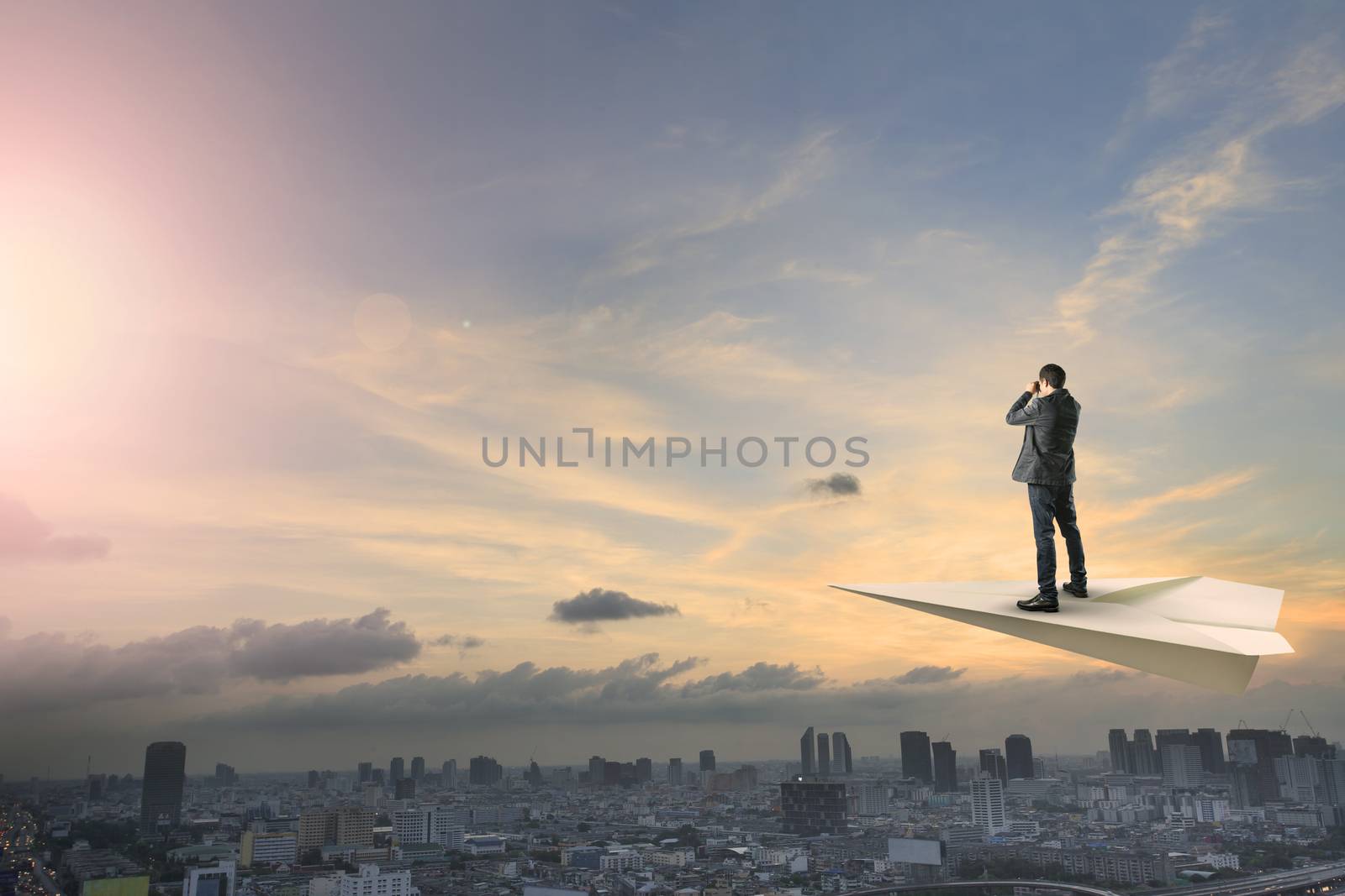 business man on paper plane flying above urban scene spying shot by binocular lens ,business conception concept