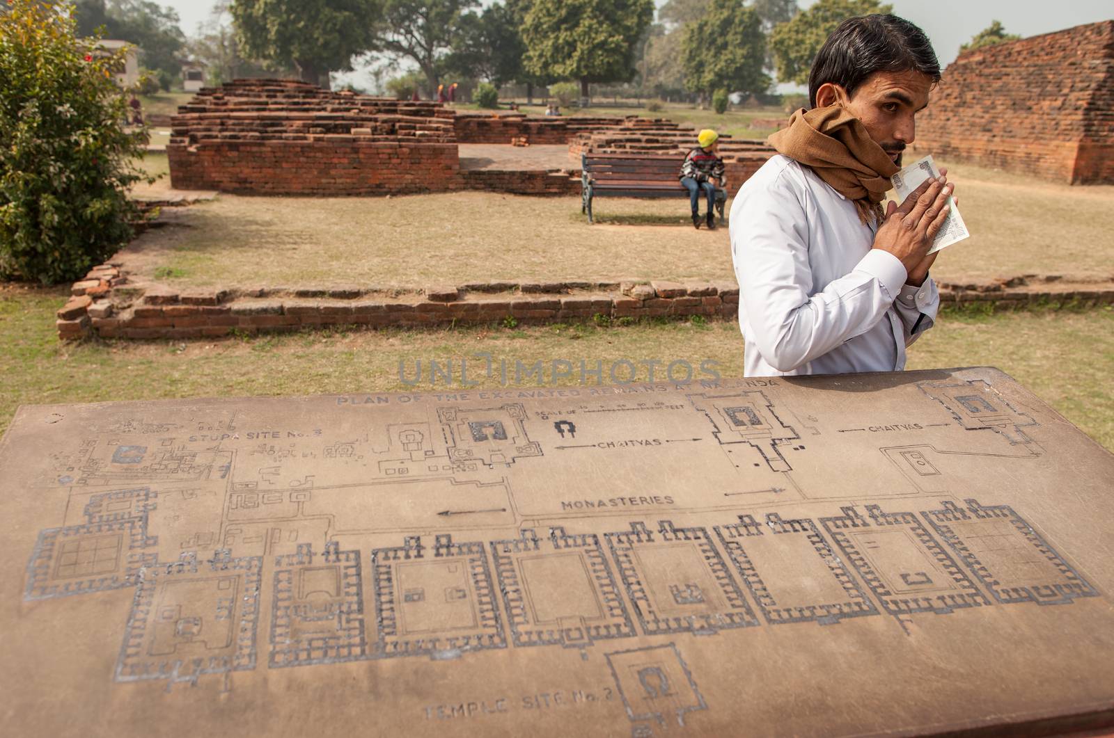 Archaeological heritage of India, ruins of university of Nalanda on February 2, 2014. At a stone with the scheme of excavation, the Indian guide has earned reward.
