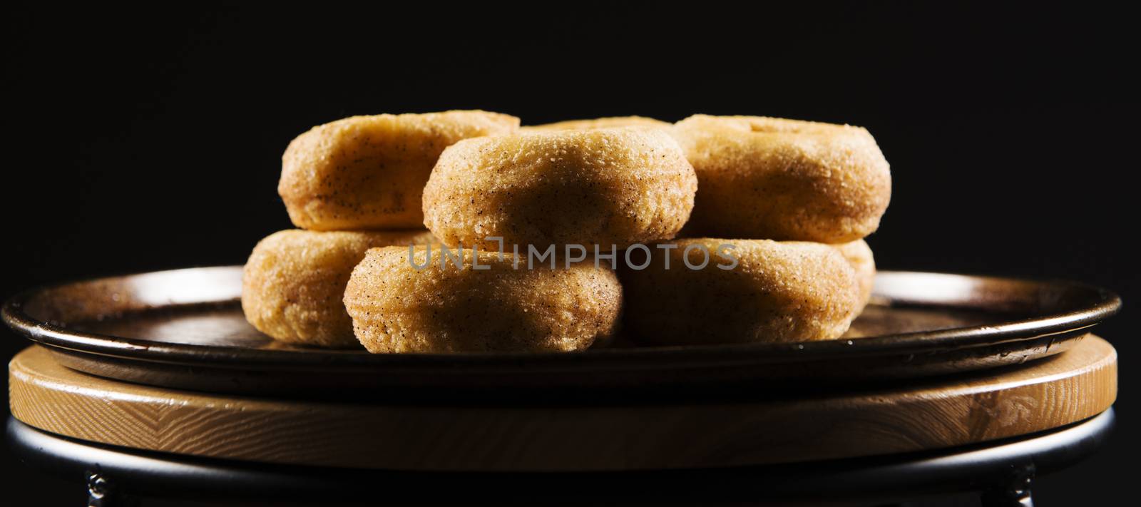 Fresh baked cinnamon donuts on a rustic metal baking tray.