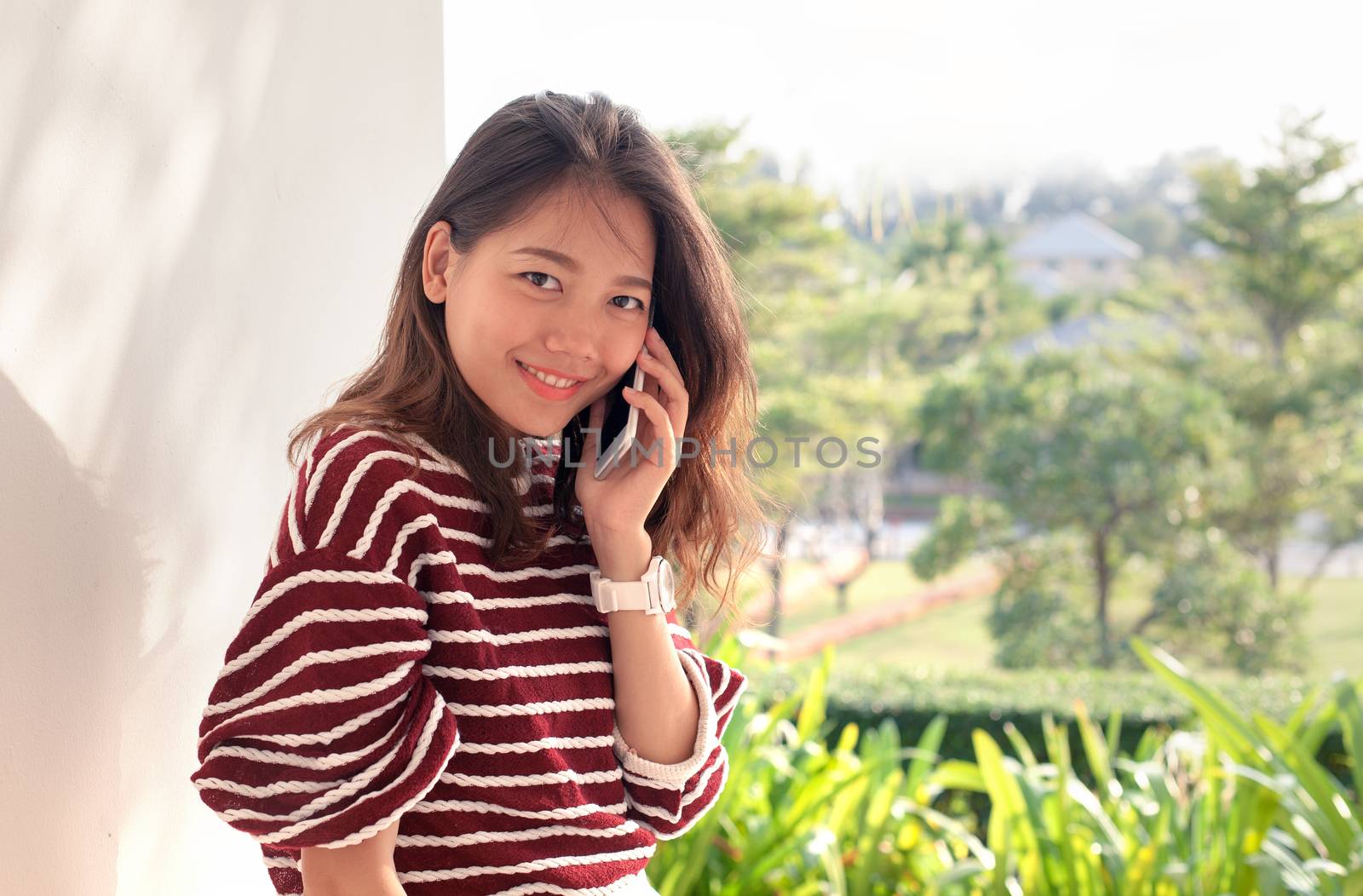 younger asian woman talking on smart phone with happiness emtion by khunaspix