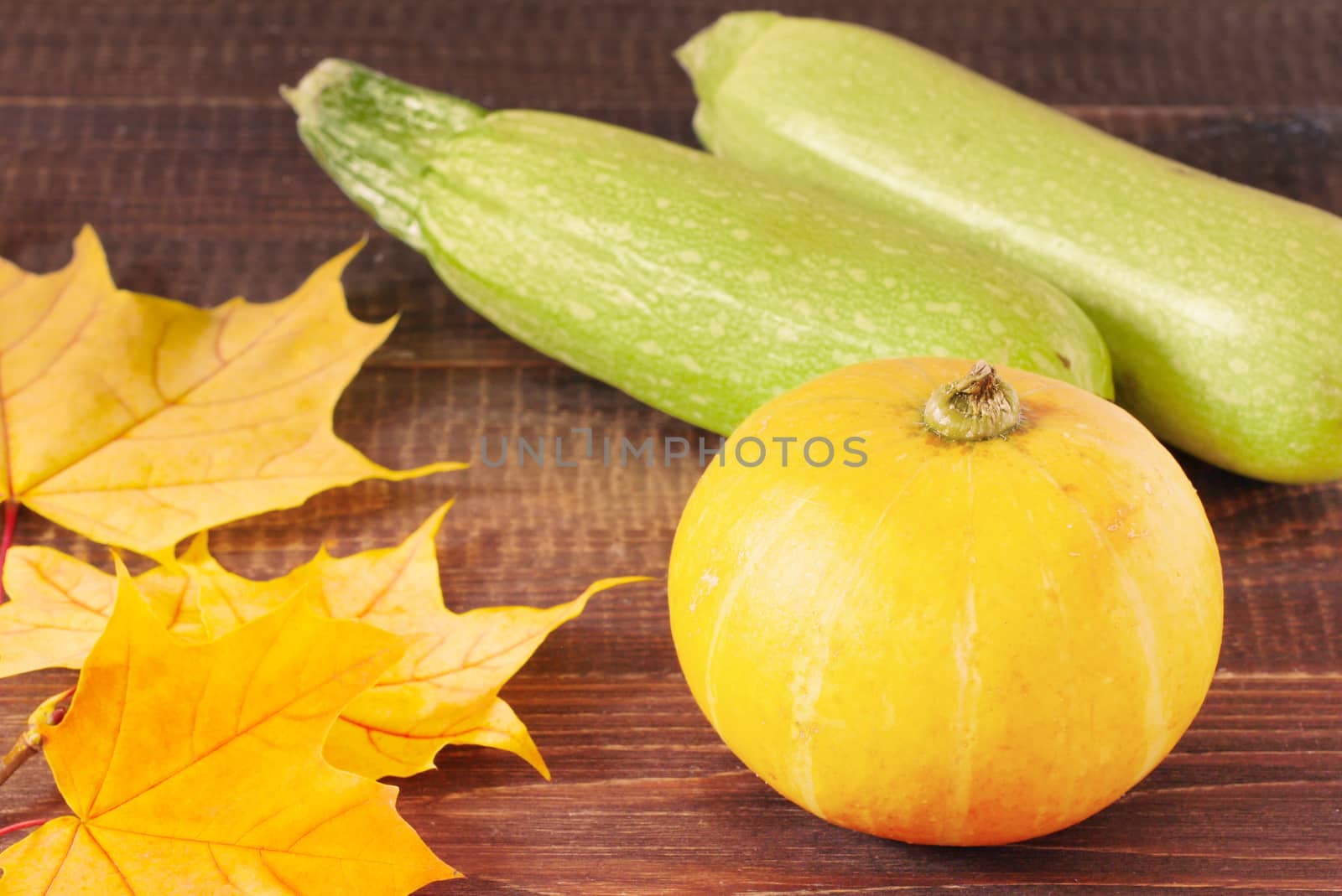 Pumpkin and zucchini on wooden table with autumn leaves. Food and drink, holidays, halloween concept