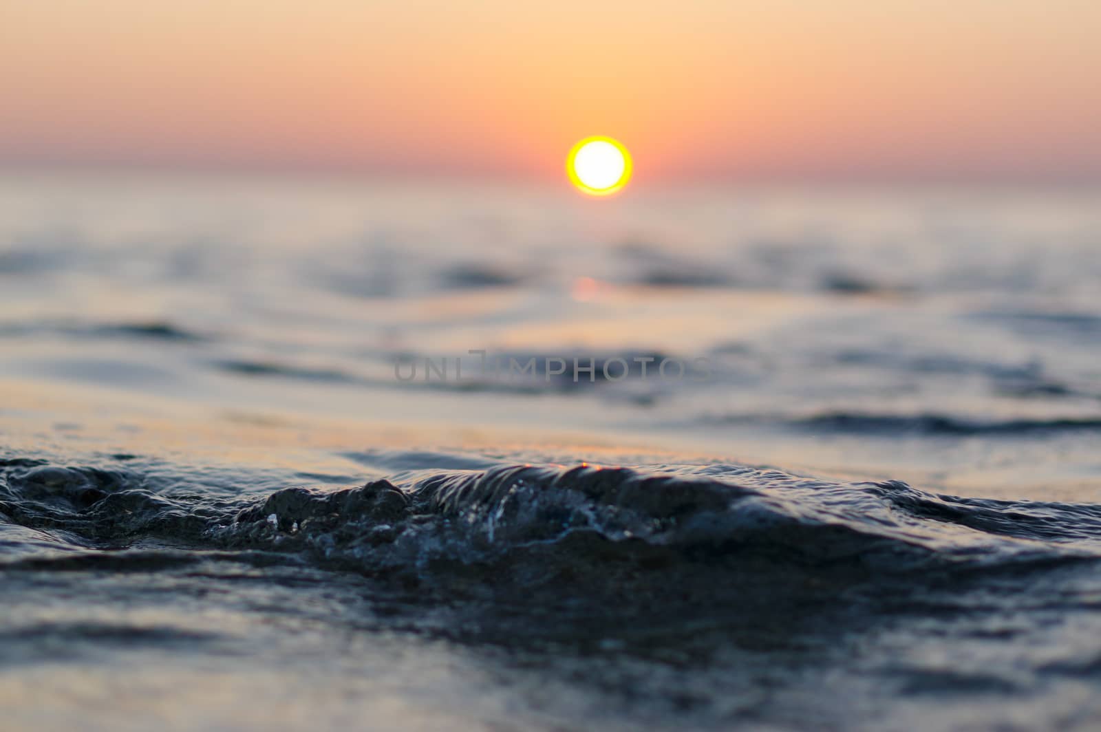 sea wave closeup at sunset time with red and orange sun reflection on the water. nature abstract blurred background. Phuket island, Thailand.