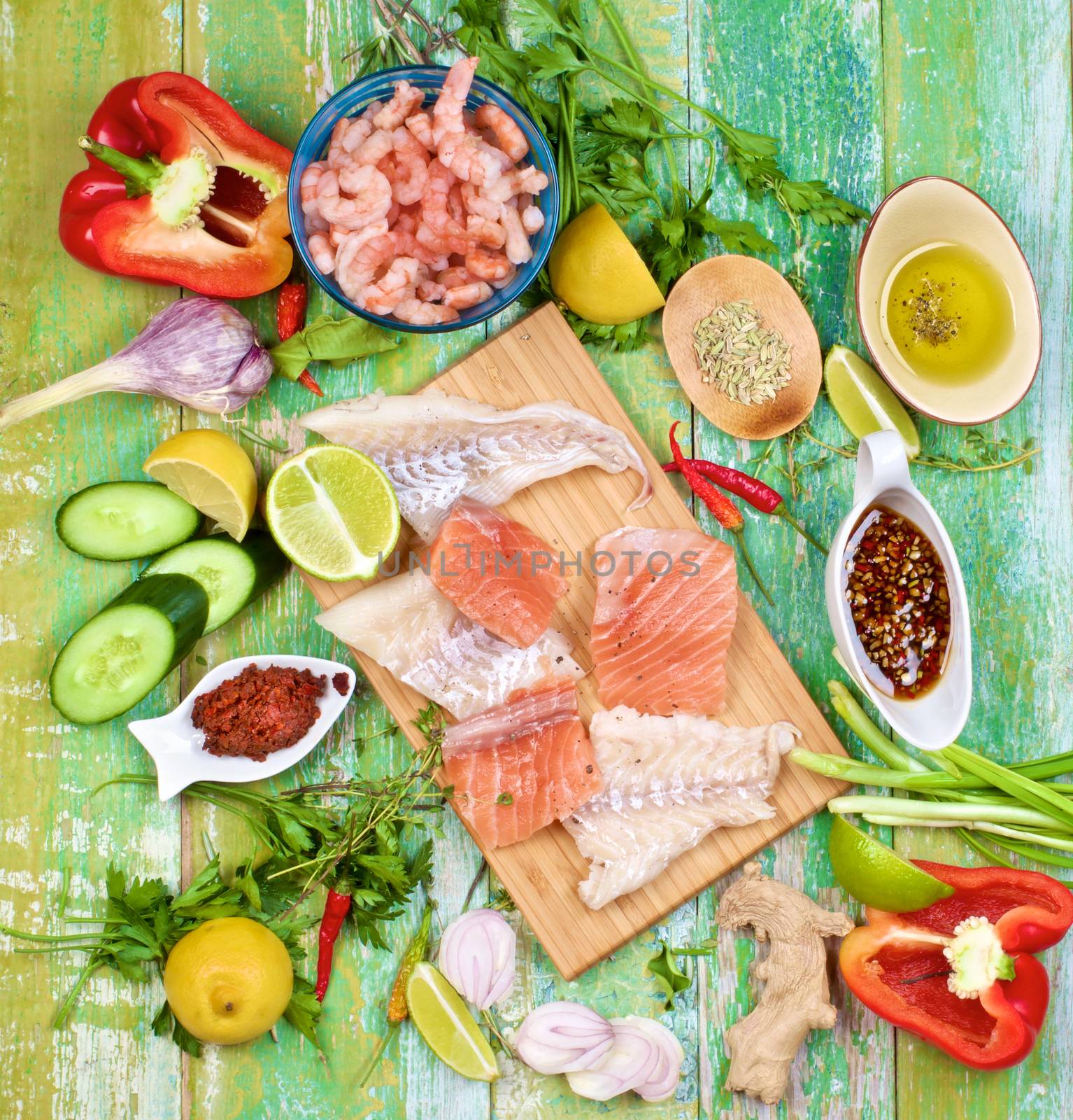 Raw Ingredients of Thai Fish Cakes with Vegetables, Spices, Herbs, Fruits, Prawns and Delicious Fillet of Salmon and Cod closeup on Cracked Wooden background. Top View