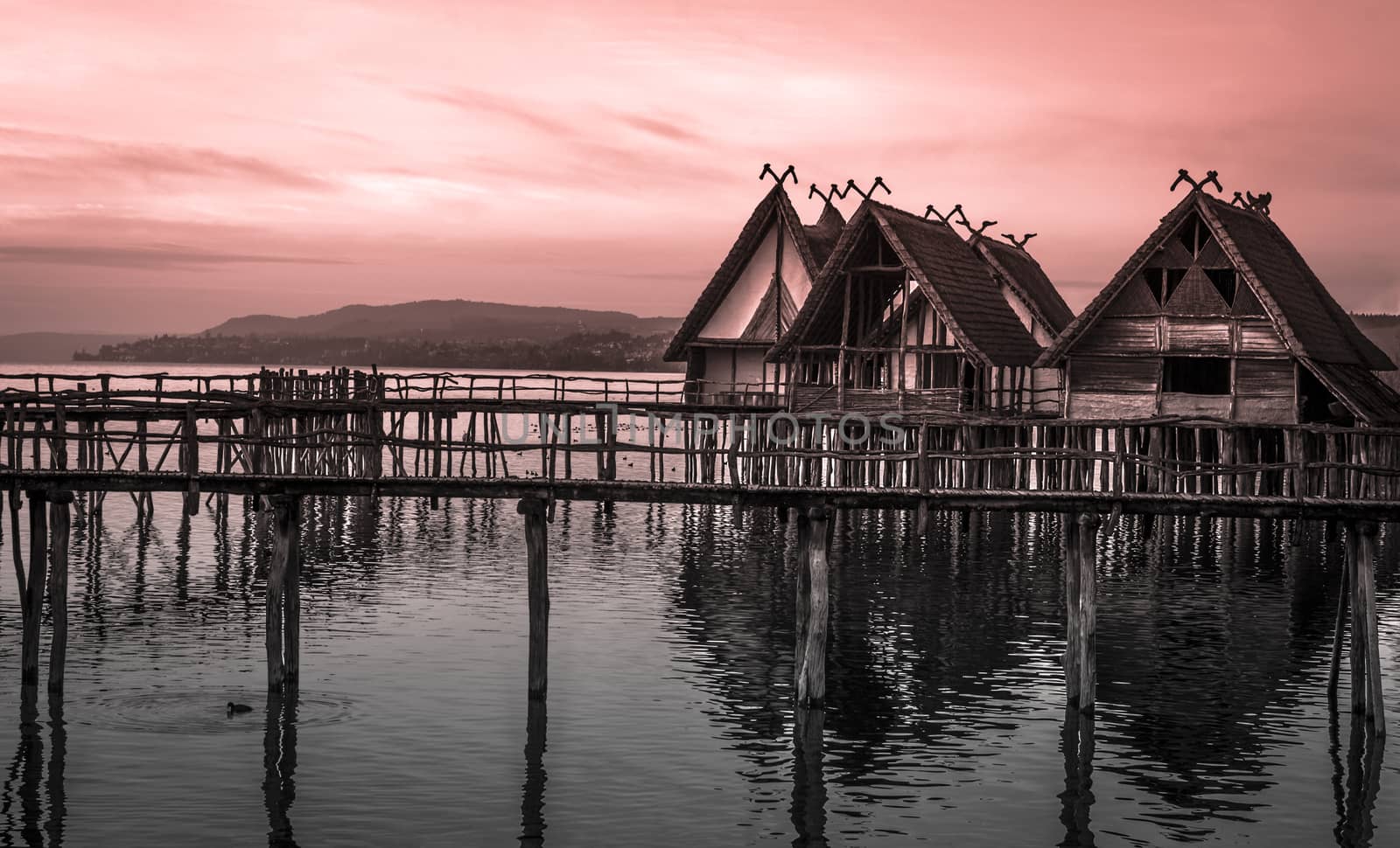 Thatched cottages suspended on stilts over lake by YesPhotographers