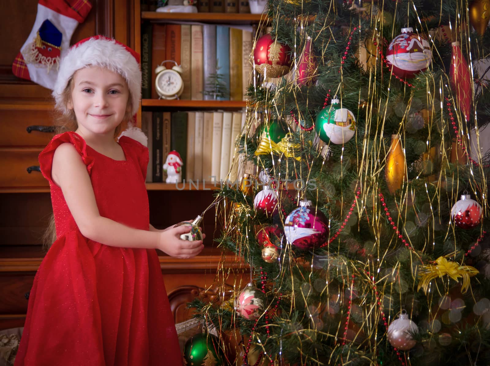 Happy girl holding ball and admiring Christmas tree