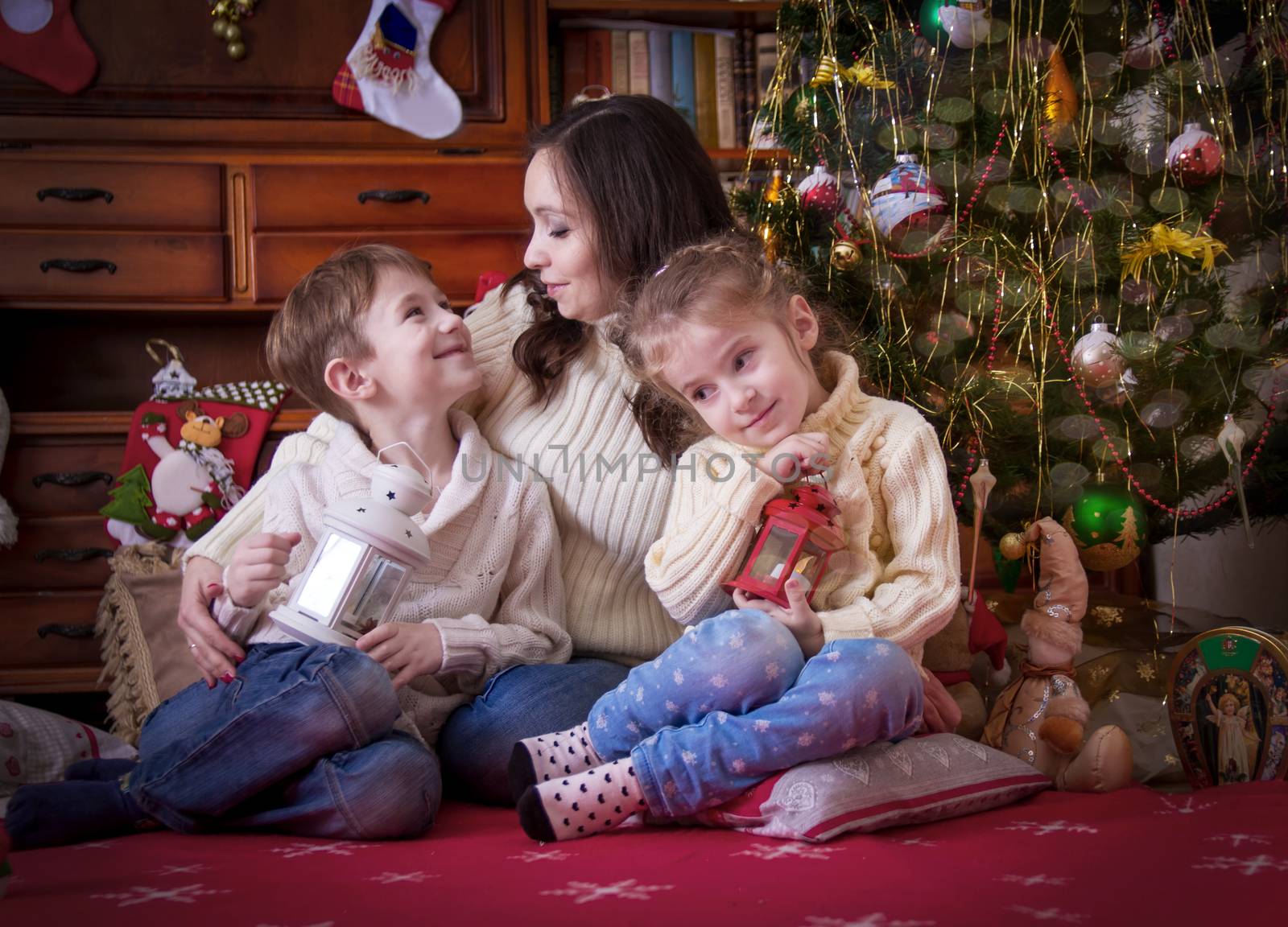 Happy mother with two kids under Christmas with lantern