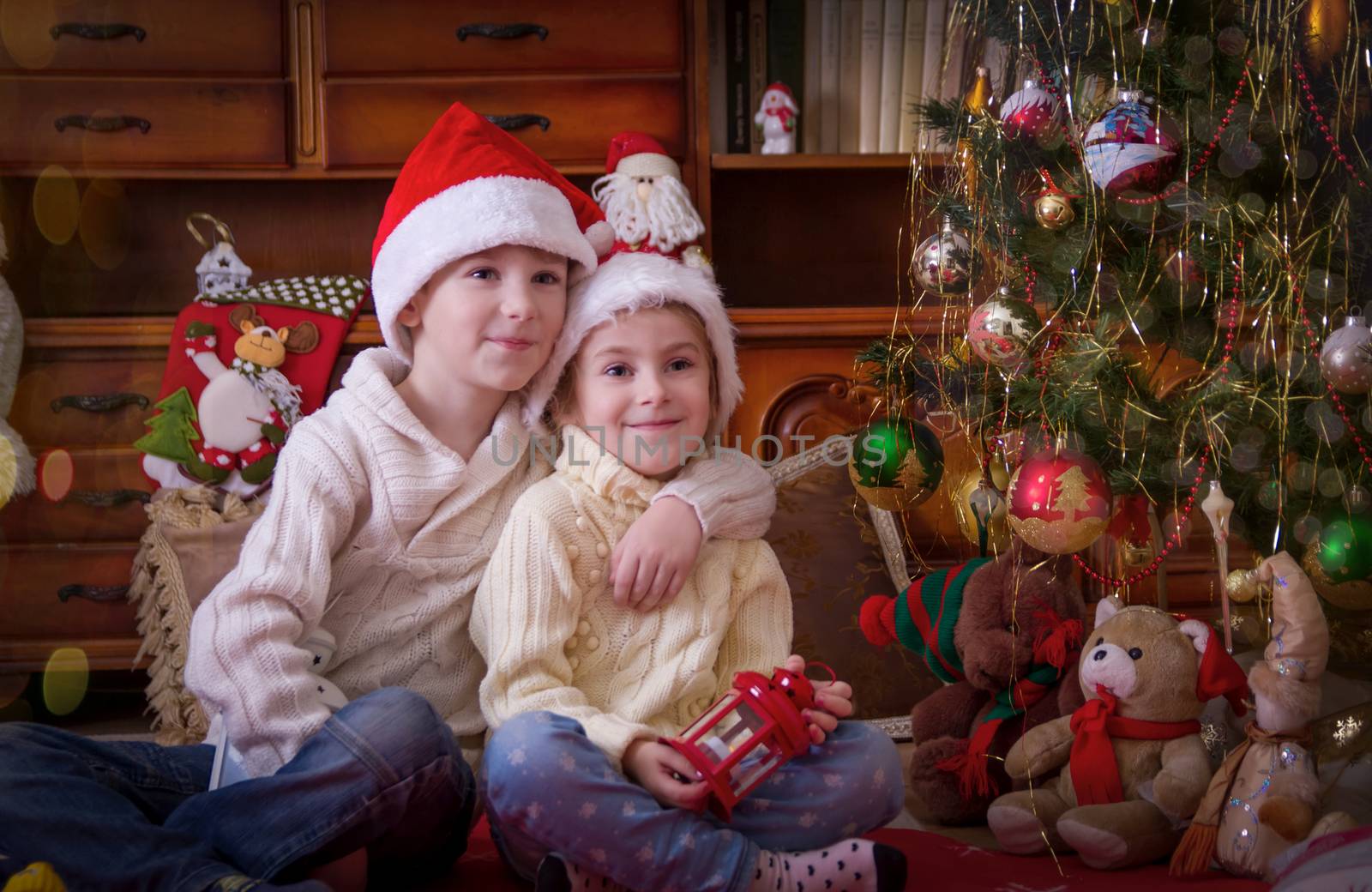 Sister and brother sittting under Christmas tree by Angel_a