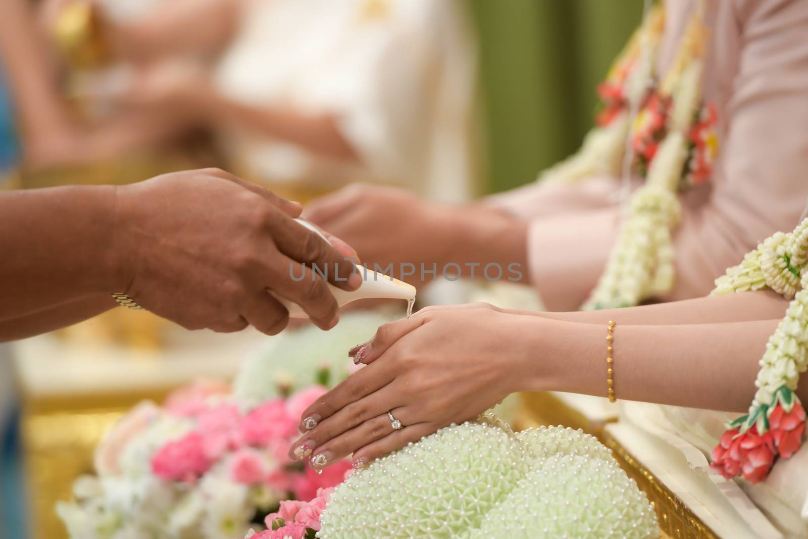 Hands pouring blessing water into bride's hands, culture Thai wedding.