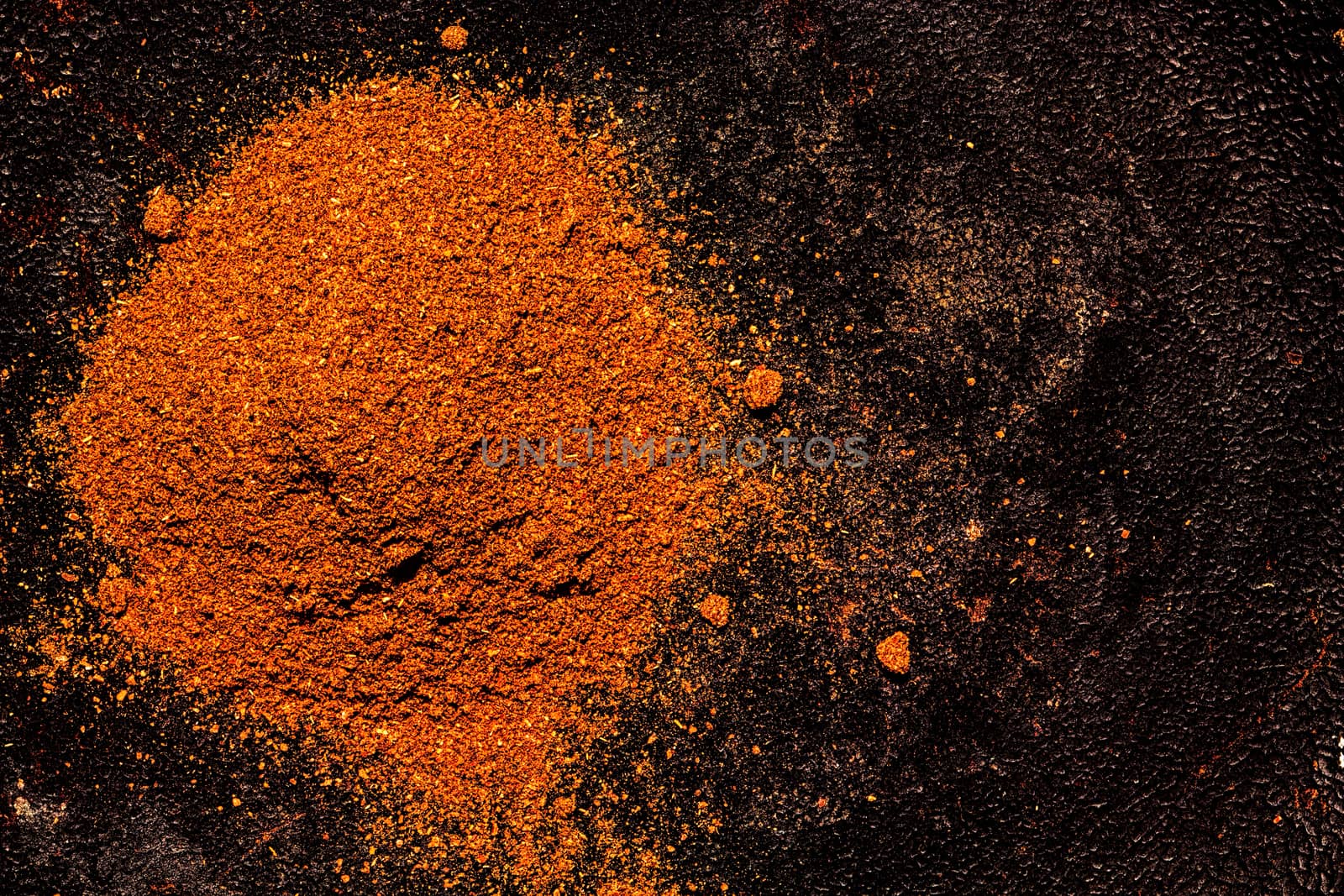 Pile of ground paprika on a textured dark background. Handful of fragrant spicy seasonings - top view with copyspace.