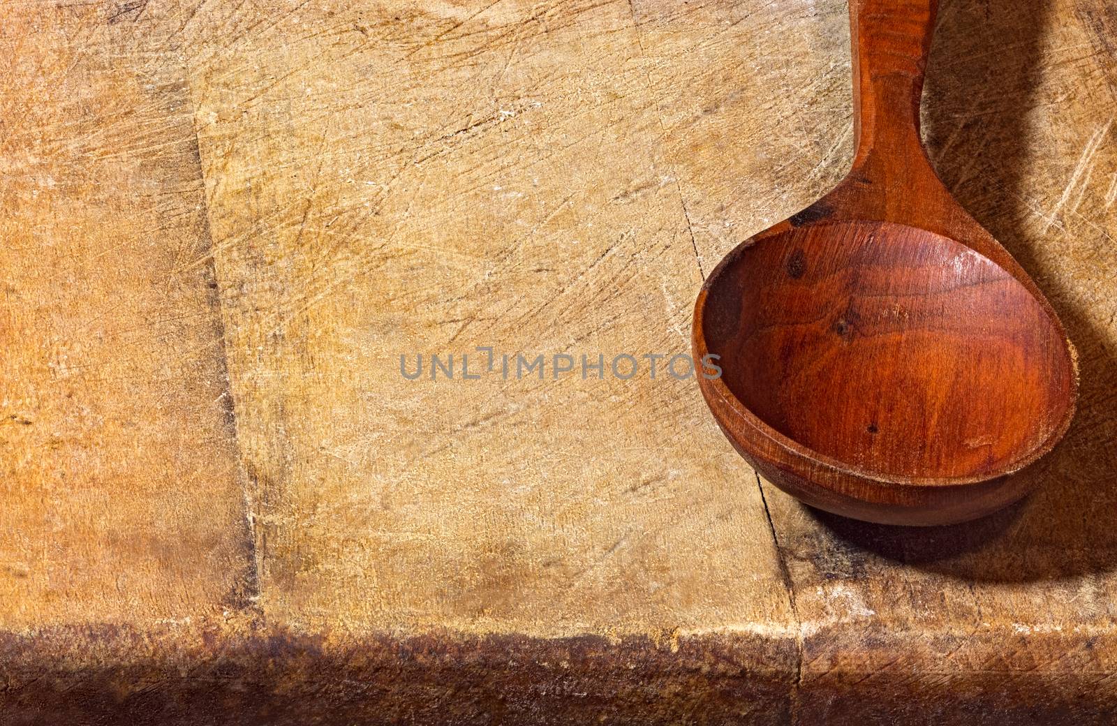 Empty wooden spoon lying on a rough wooden background. Rural style still live close up image with copyspace.