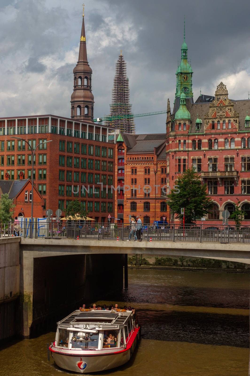 HAMBURG, GERMANY - JULY 18, 2015: ferry on the canal of Historic Speicherstadt houses and bridges at evening with amaising skyview over warehouses, famous place Elbe river. by evolutionnow