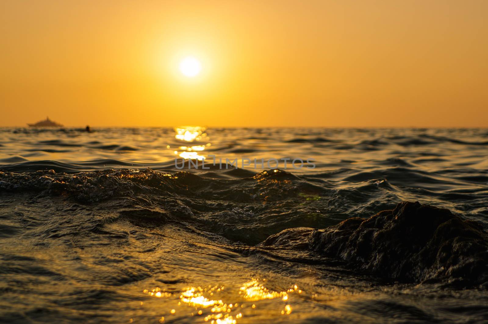 sea wave close up at sunset time with red and orange sun reflection on the water. nature abstract blurred background. Phuket island, Thailand by evolutionnow