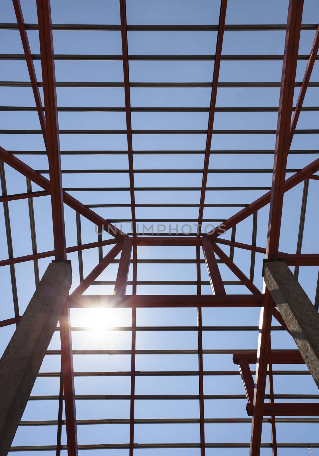 metal structure of house roof in home construction site and sun shining on blue sky use for construction business and construction industry 