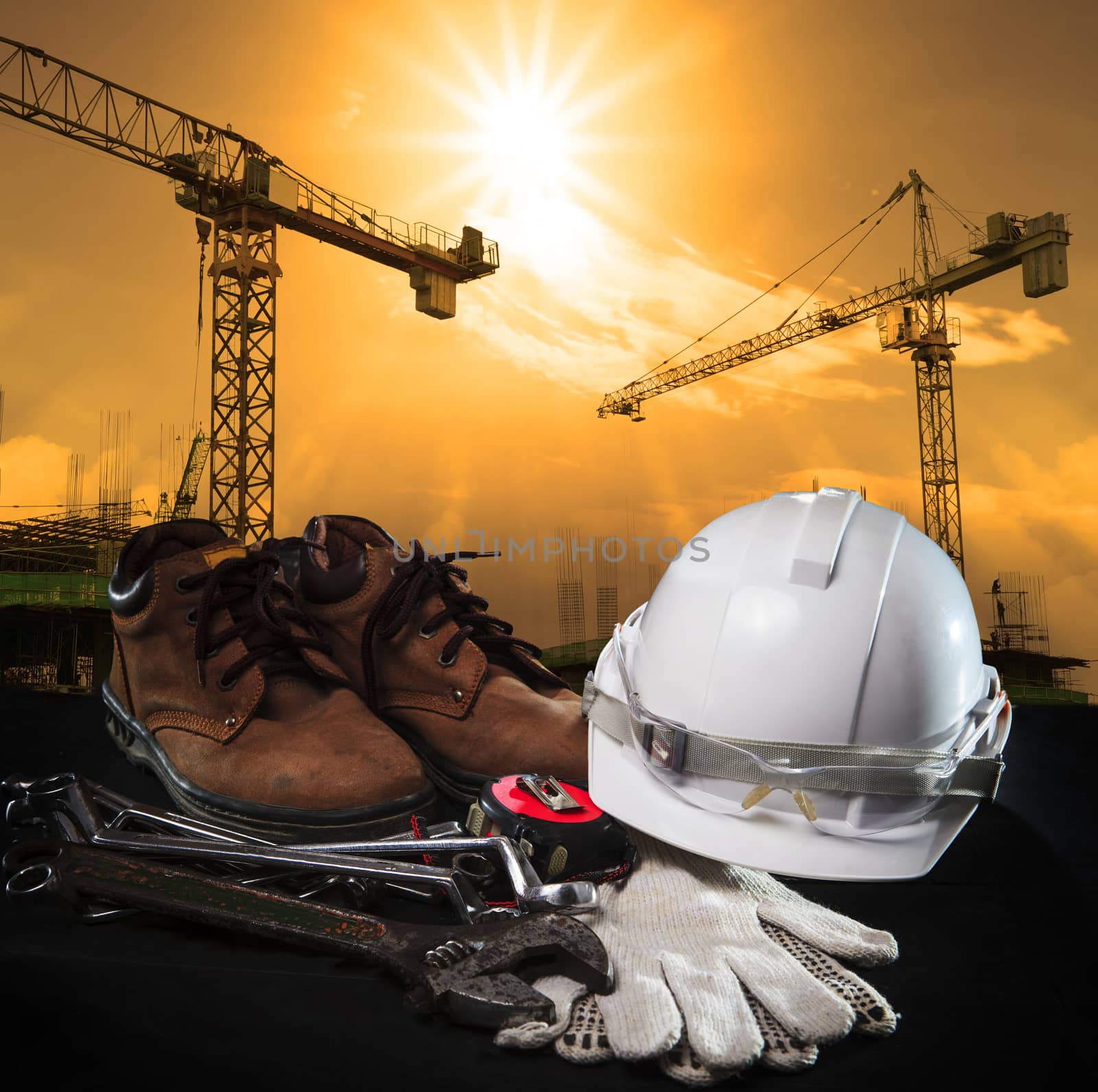 helmet and construction equipment with building and crane against dusky sky use for construction business theme