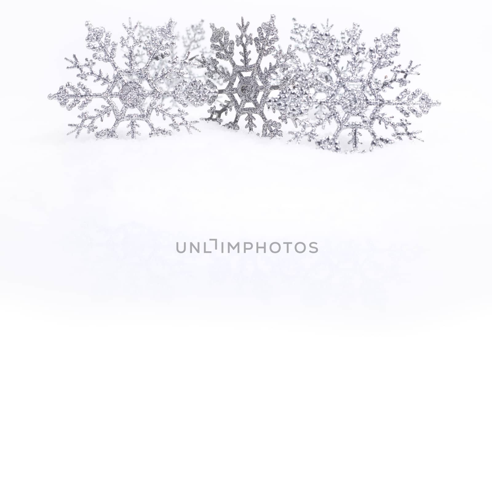 Decorative silver snowflakes on snow, white copy space