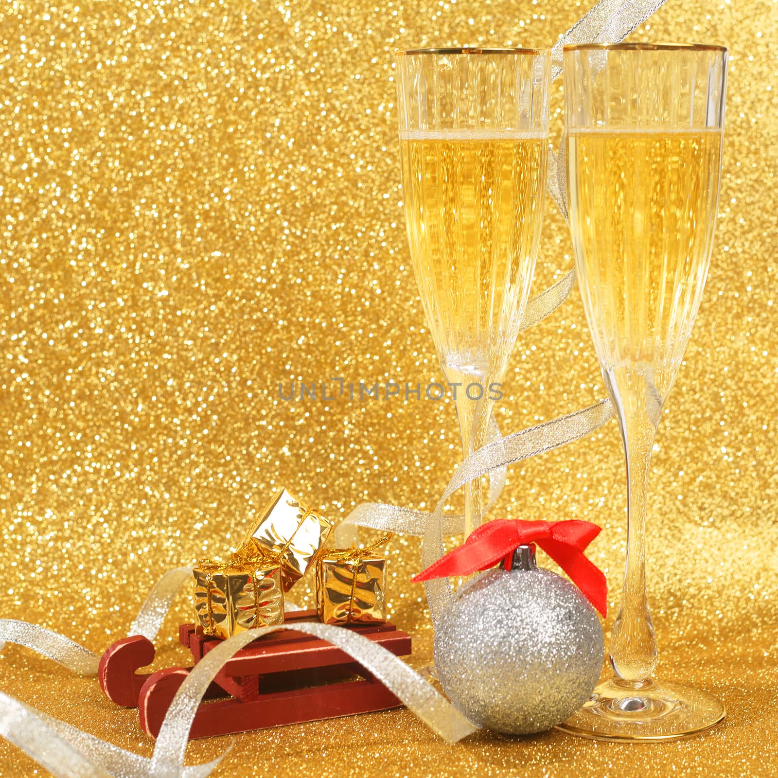Two glasses of champagne with golden glitter lights on background