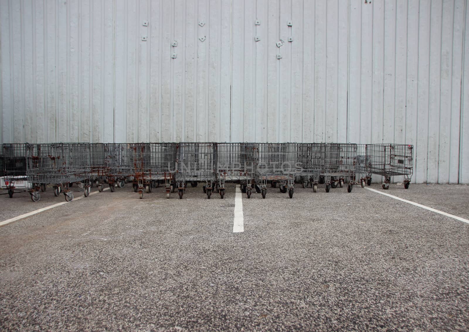 Industrial Iron Trolleys at Parking  Lot with White Stripes by HoleInTheBox