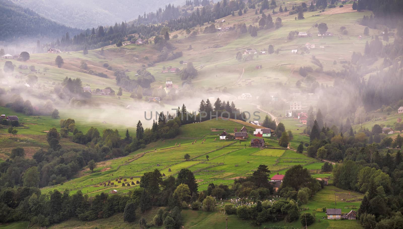 Alpine village in mountains. Smoke and haze over the hills in Carpathians.