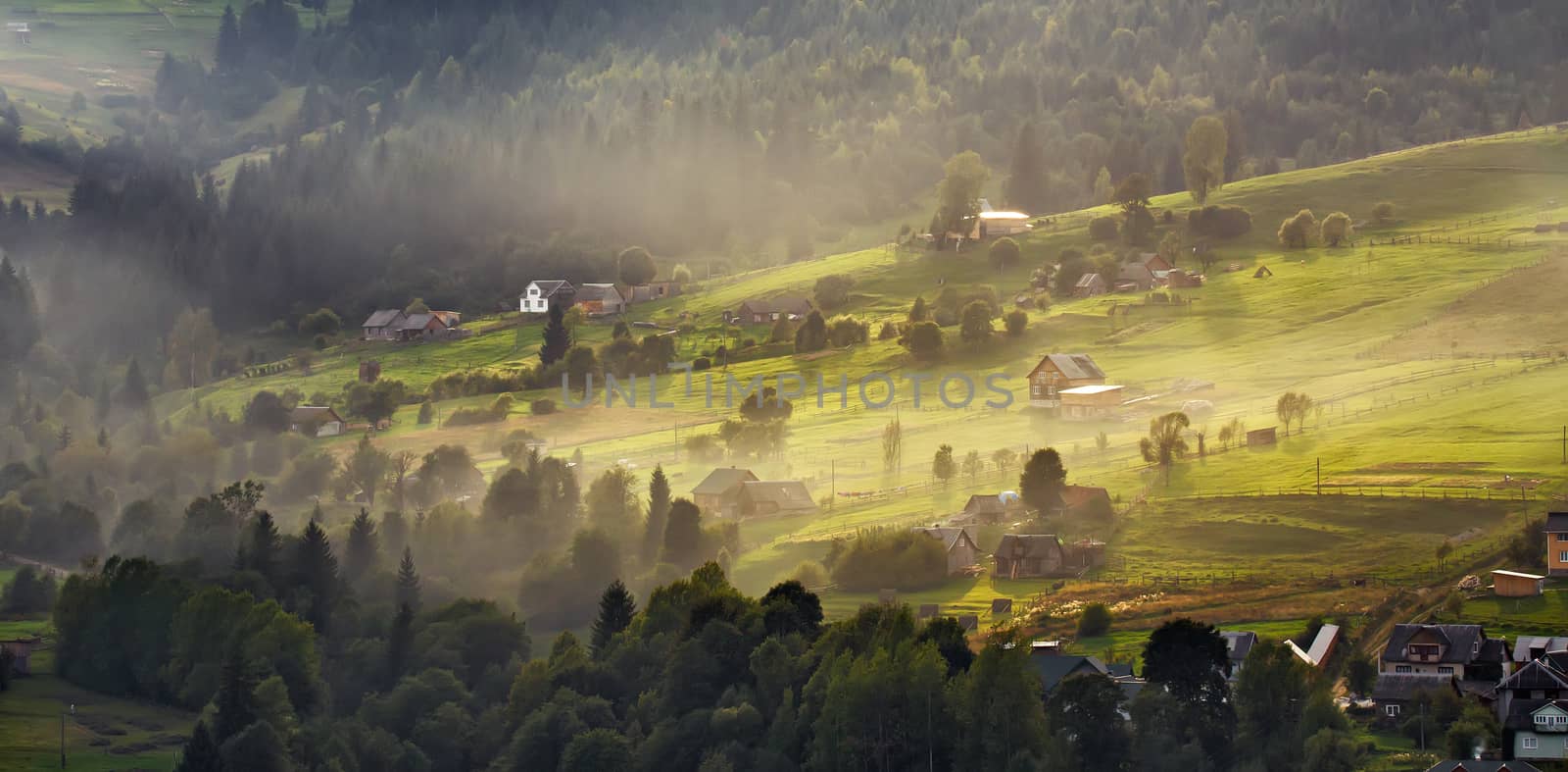 Alpine village in mountains. Smoke and haze over the hills in Carpathians.