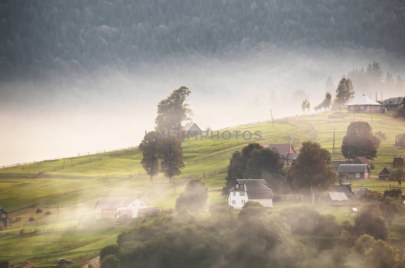 Alpine village in mountains. Smoke, bonfire and haze over the hills in Carpathians.