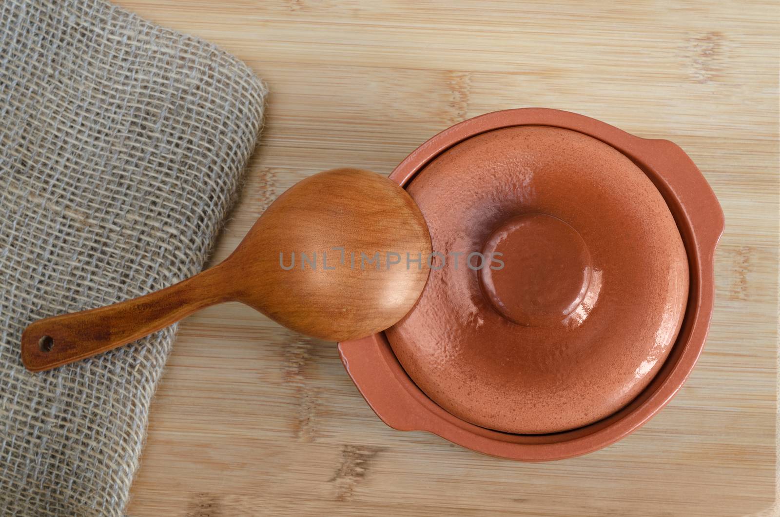 Ceramic pot and a wooden spoon. On the Board, top view.