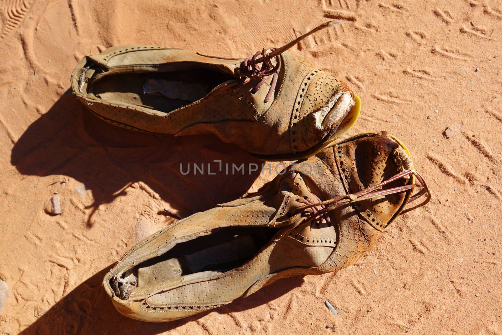 old dirty pair of shoes on sand background                               