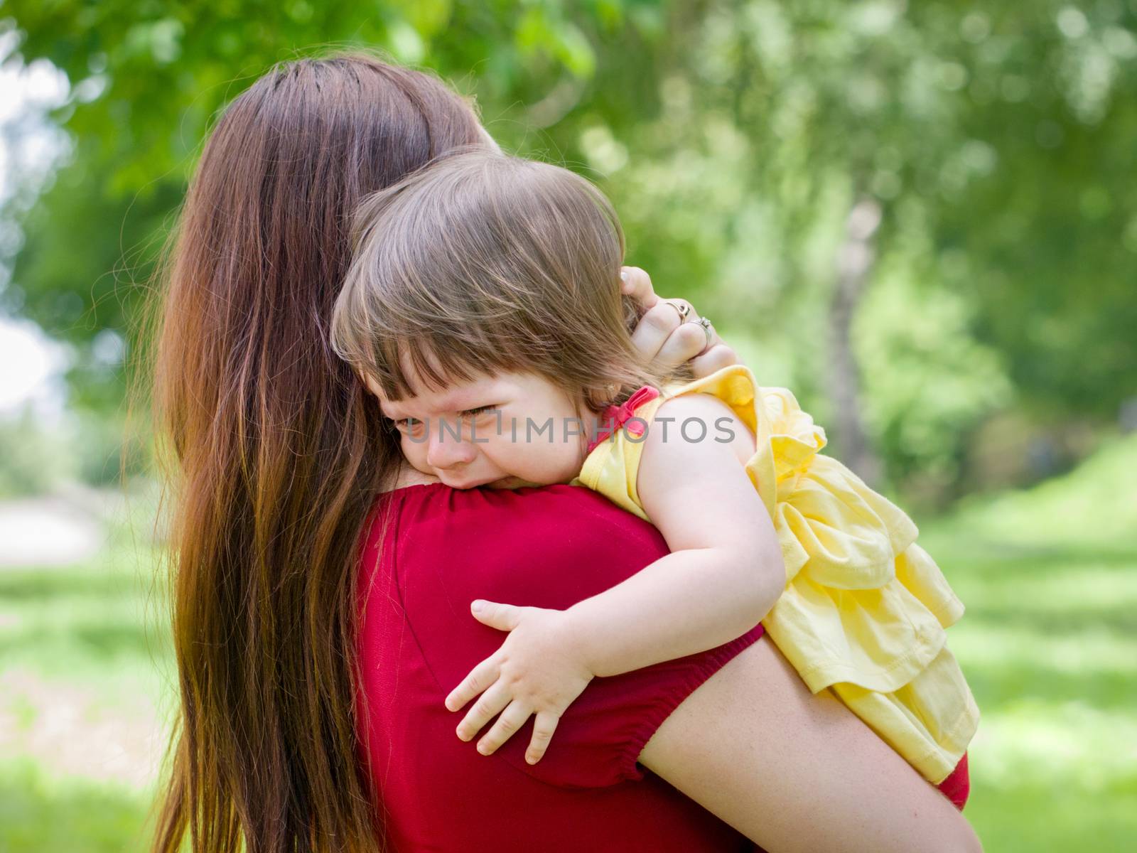 Mother holding her crying one-year old baby girl with tears close up