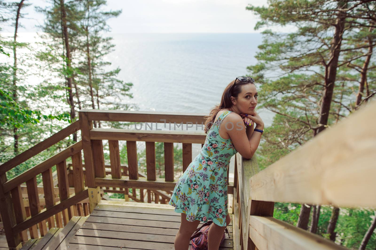 Brunette girl sitting on the wooden stairs in park and smiling