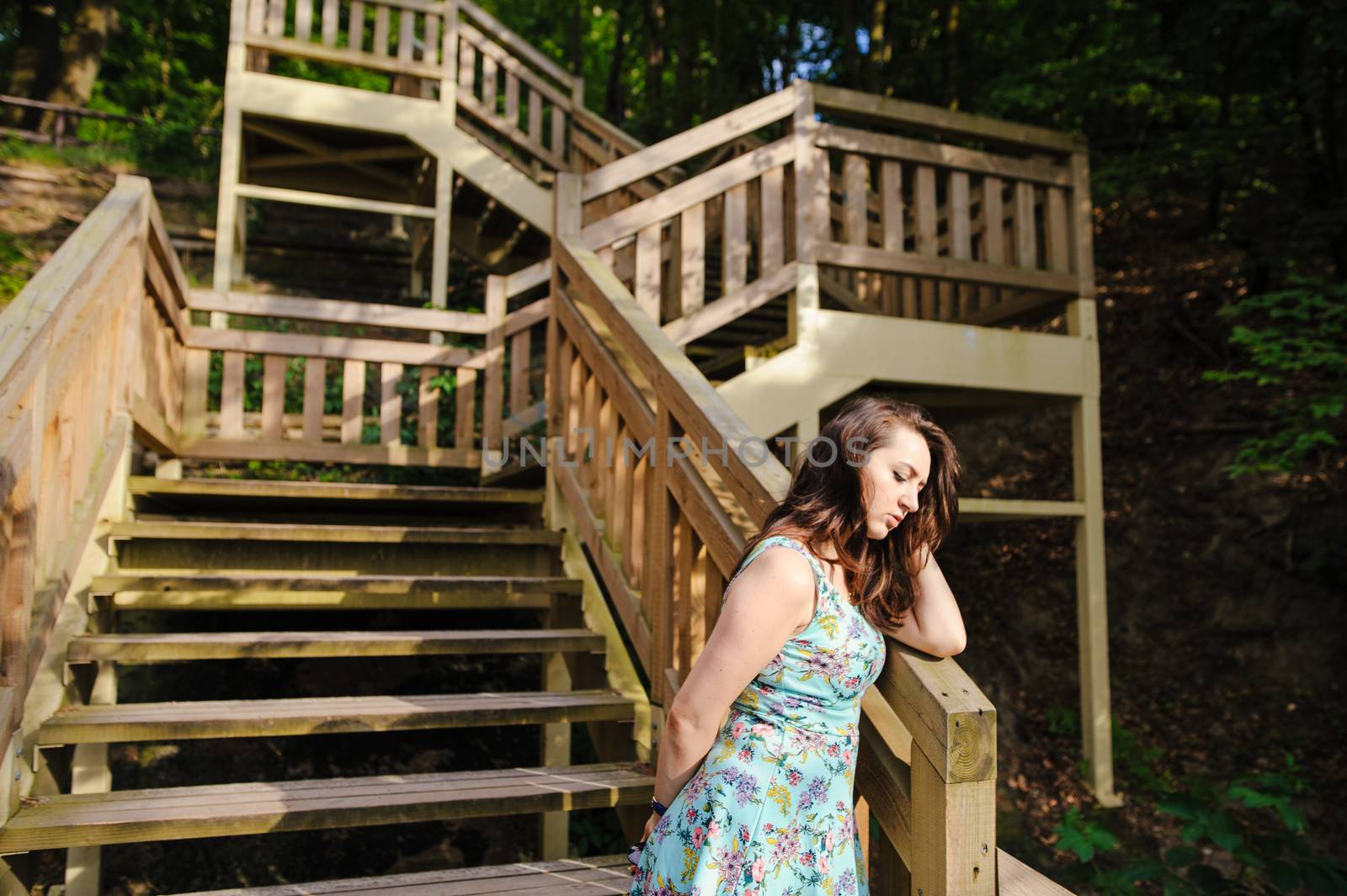Brunette girl sitting on the wooden stairs in park and smiling
