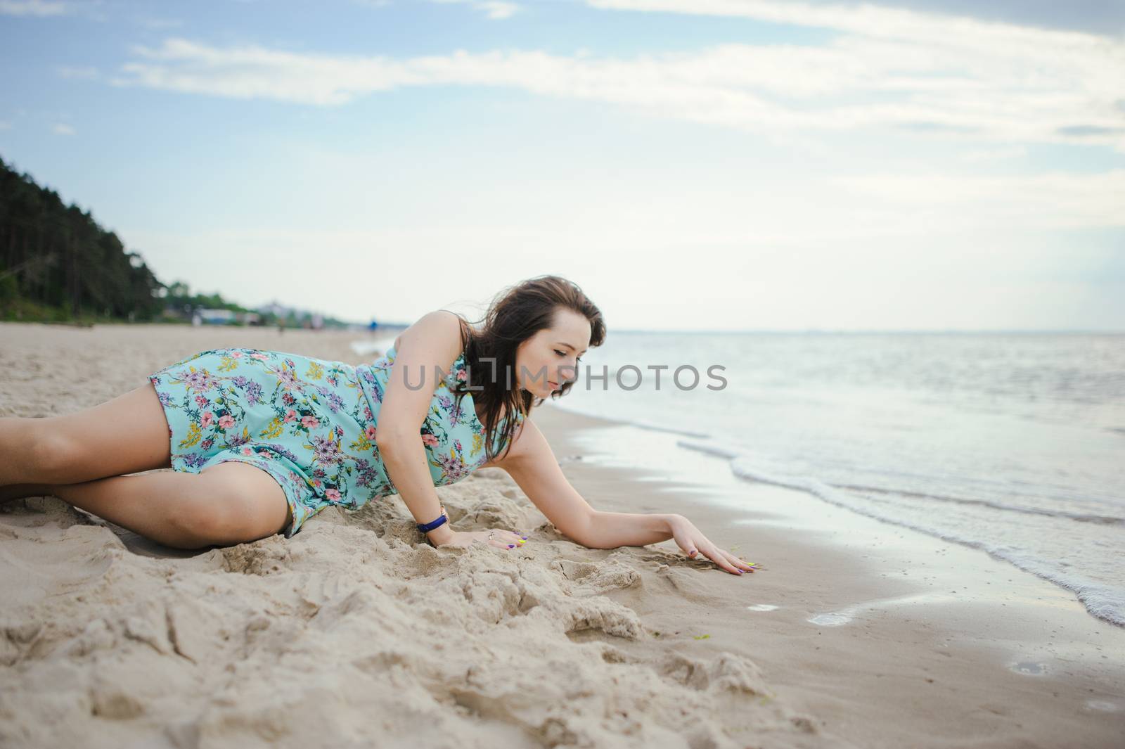 Young attractive brunette woman on a beach wearing dress