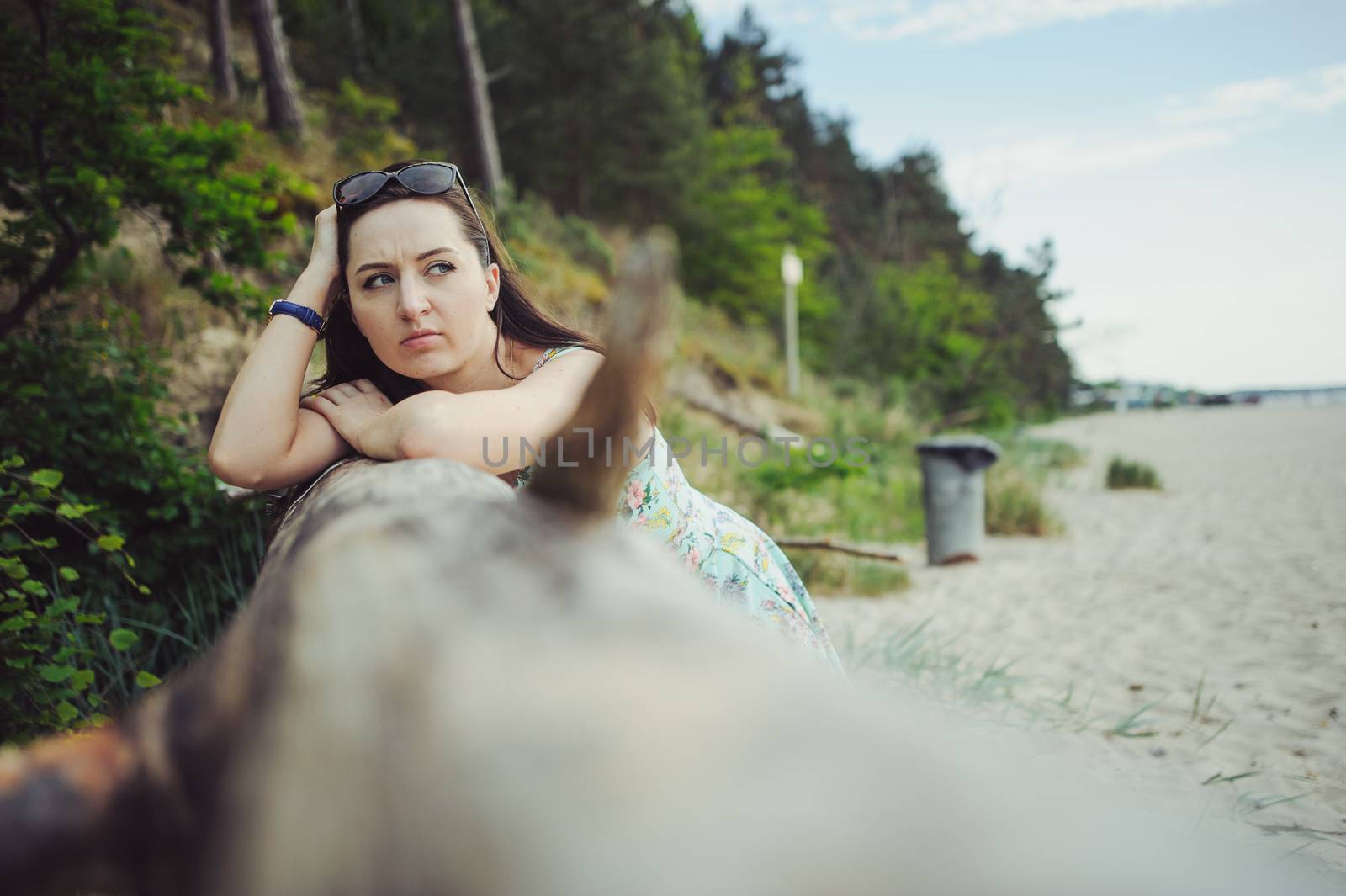 Young attractive brunette woman on a beach wearing dress