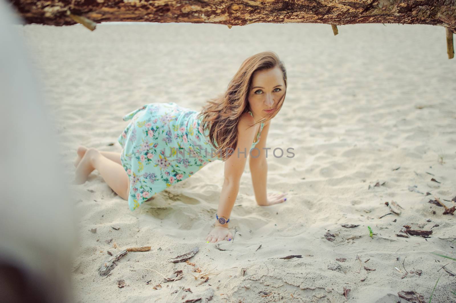 Young attractive brunette woman on a beach wearing dress