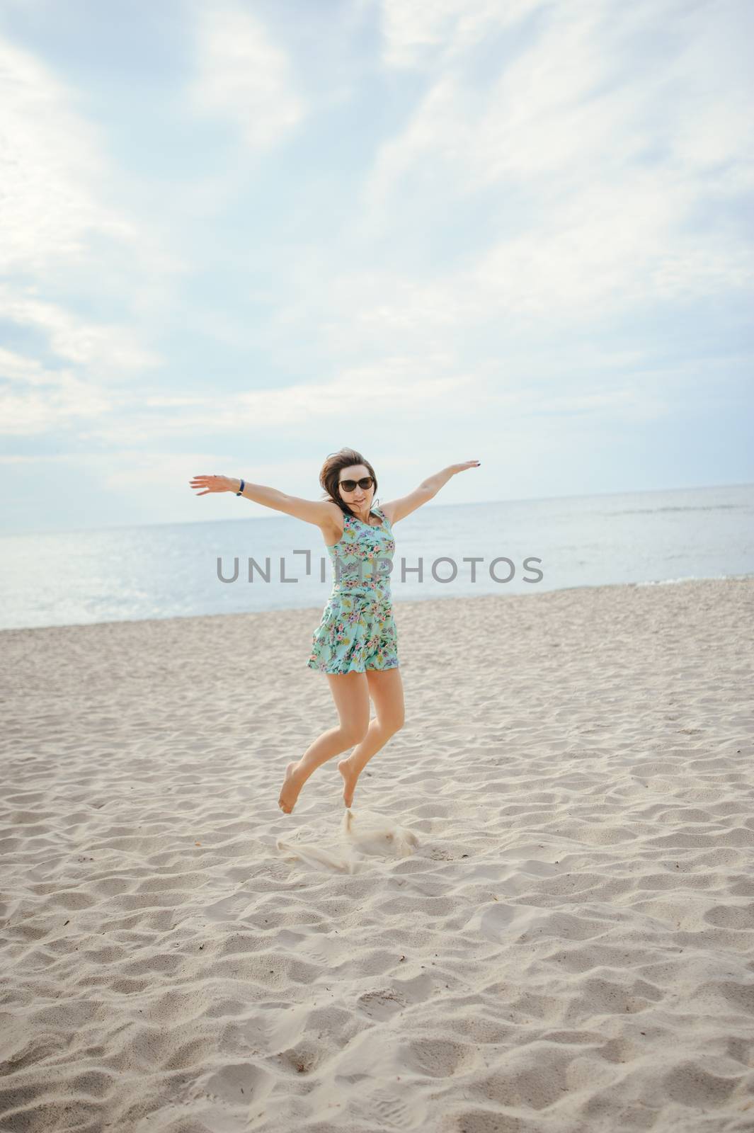 Young attractive brunette woman on a beach wearing dress