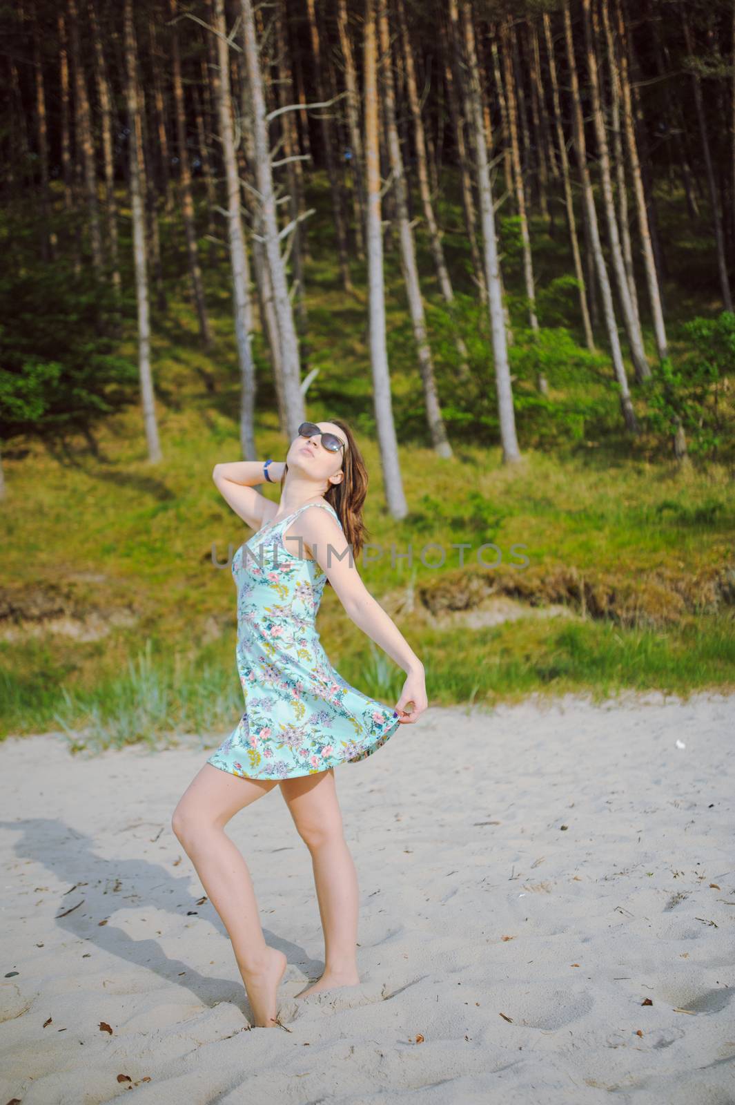 Young attractive brunette woman on a beach wearing dress
