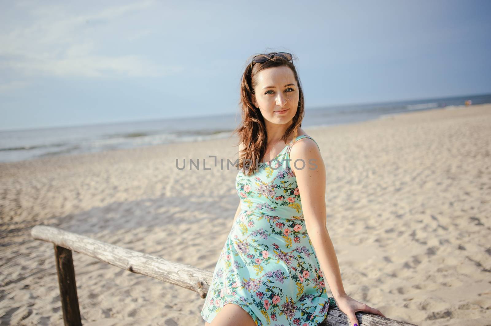 Young attractive brunette woman on a beach wearing dress