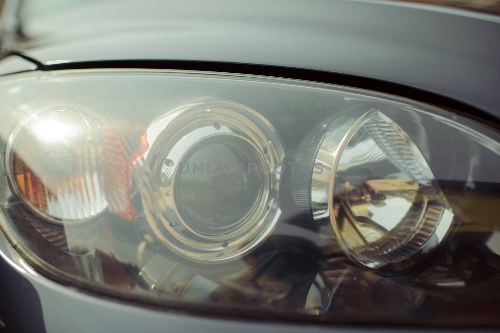 Closeup of front car xenon headlight with lights reflections