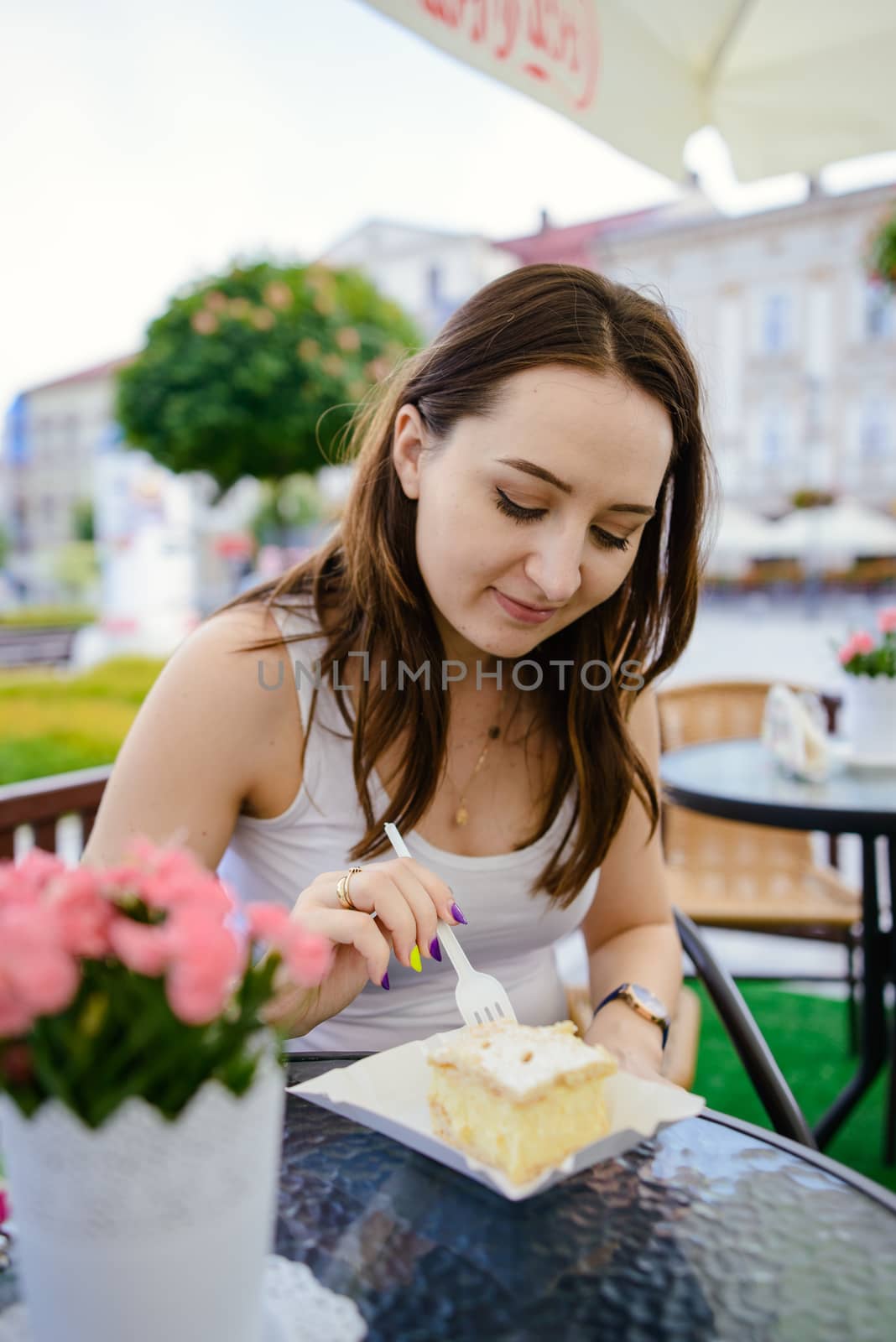 girl eating piece of fondant cake on table, outdoor restaurant
