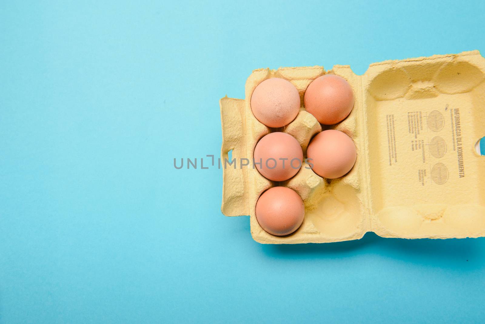 View of opened box of chicken eggs, blue background