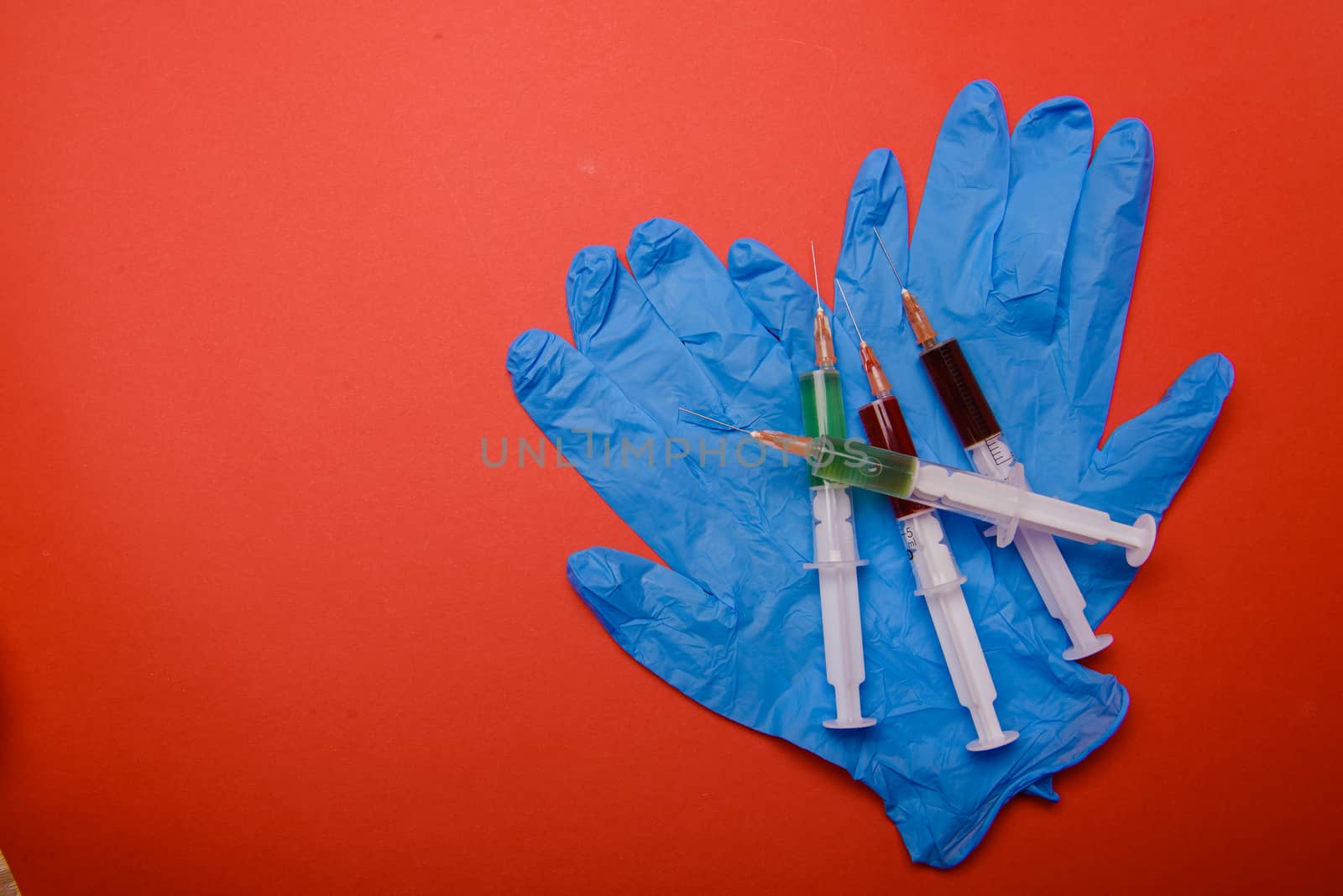 Hand in glove with syringe on red background. Injections.